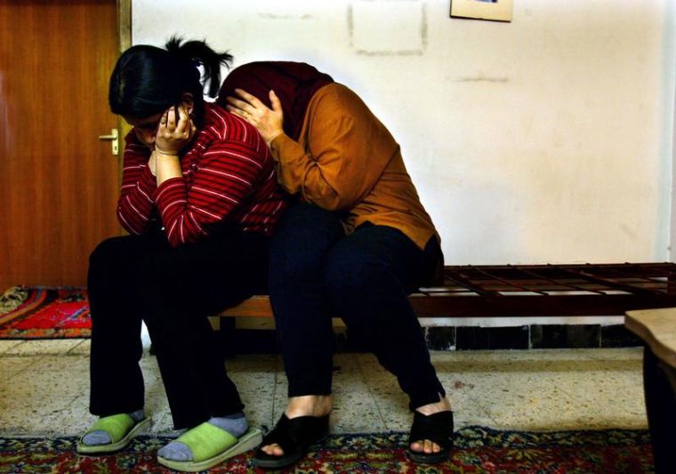WAR BAGHDAD FAMILY As bombs fall not far from their homes in the Arasat neighborhood, Fatima, age 14, left, and her mother Jinan Abdul Hamid, 48, huddle together in their living room. Photo by Carolyn Coles/Los Angeles Times