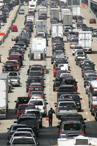 A pedestrian walks between traffic with a tool box trying to locate a motorist on northbound Interstate 45 in Houston on Thursday. Traffic throughout the Houston area was very heavy as residents left town before Hurricane Rita arrived. Photo By The Assoc