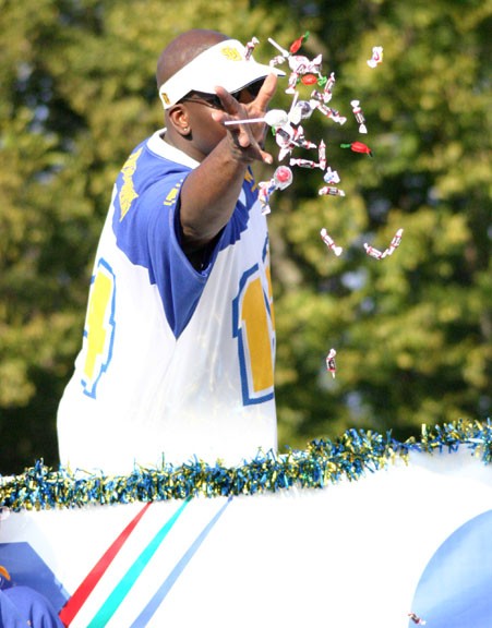 A rider on on a Cox Cable float flings candy at spectators during last year's homecoming parade. PHOTO BY ANTHONY MOORE