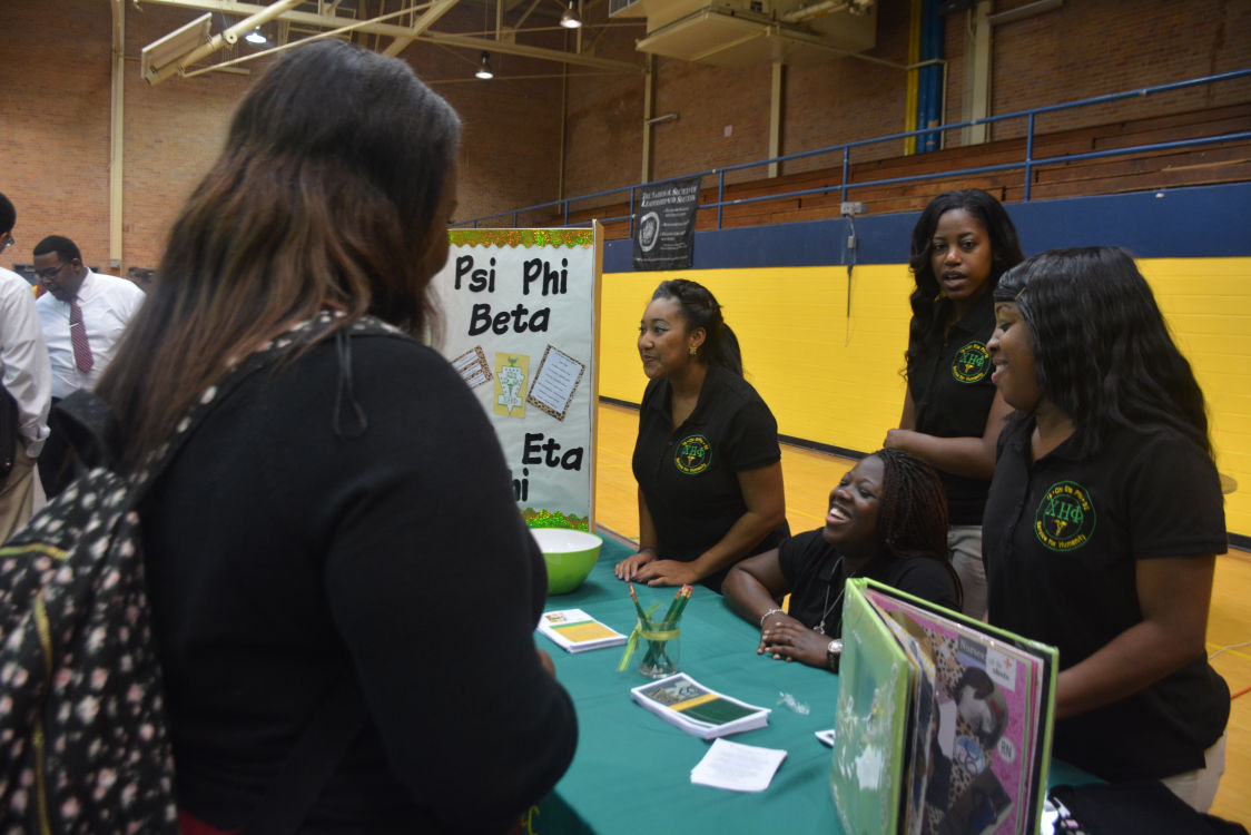 The sisters of Psi Phi Beta laugh and smile while explaining to a student the wonders of their organization.