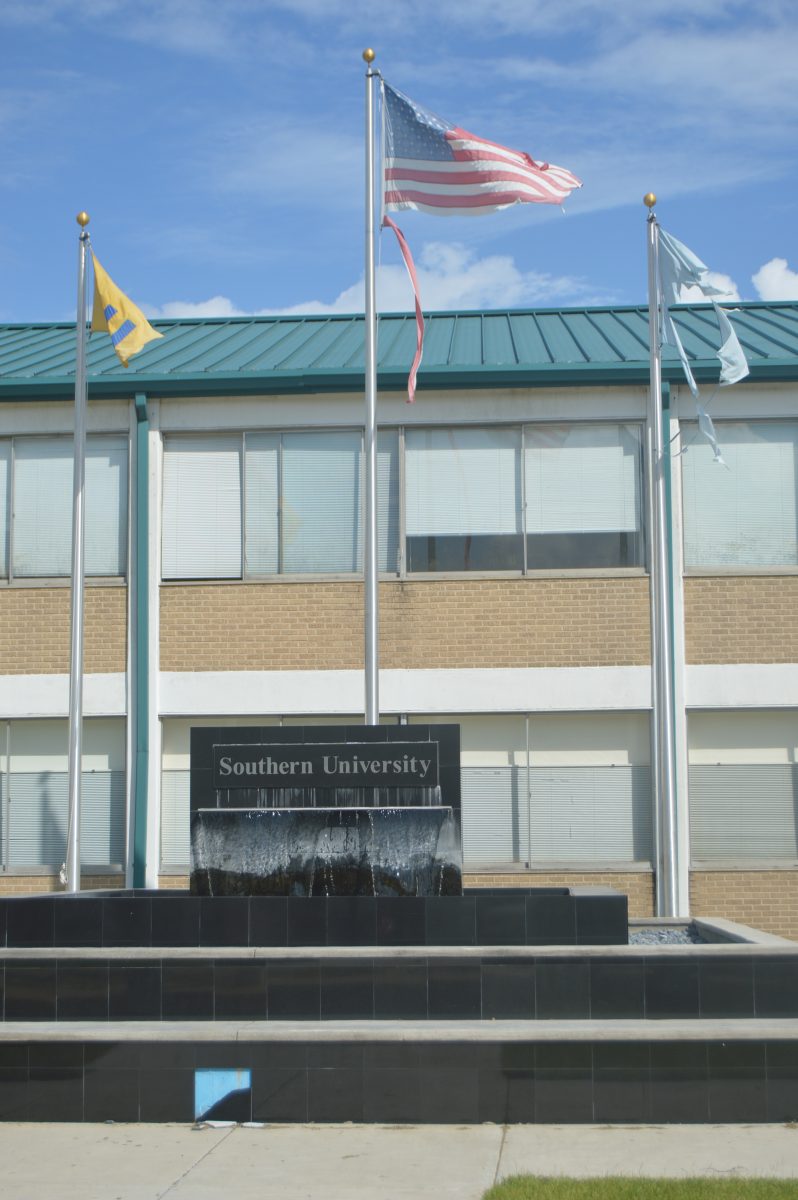 Torn Southern University flags and the American Flag hang outside of Harris Hall near the fountain across from the Smith-Brown Memorial Union.