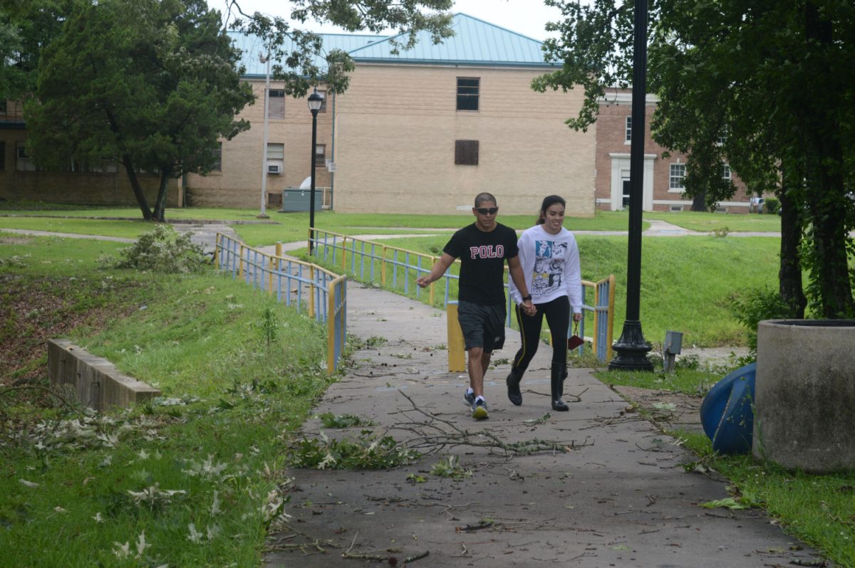 Southern university students trek through one of many locations scattered with fallen tree limbs and leaves on campus.