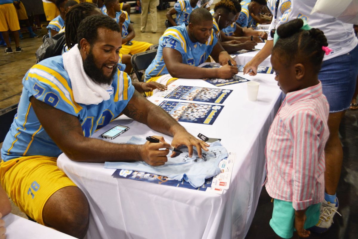 Senior Offensive Lineman, Reginald Redding, autographs a t-shirt for a tiny Jaguar Football fan during Fan Fest 2015in the F.G. Clark Activity Center.