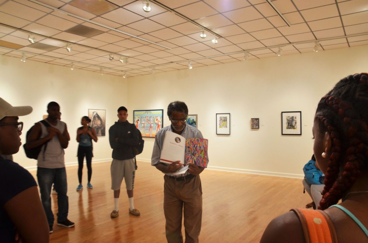 SU junior Riyon Jack (Baton Rouge, La) and freshman Imani Butler (Plaquemine, LA) listen as Dr. Henry showcases previous work September 15, 2016 at the Faculty Art Gallery Exhibit located in Hayden Hall.