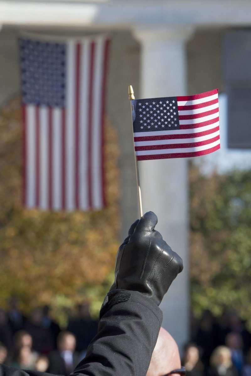 An American flag is held during the National Veterans Day Observance at Arlington National Cemetery in Arlington, Va., Sunday, Nov. 11, 2018. (AP Photo/Cliff Owen)