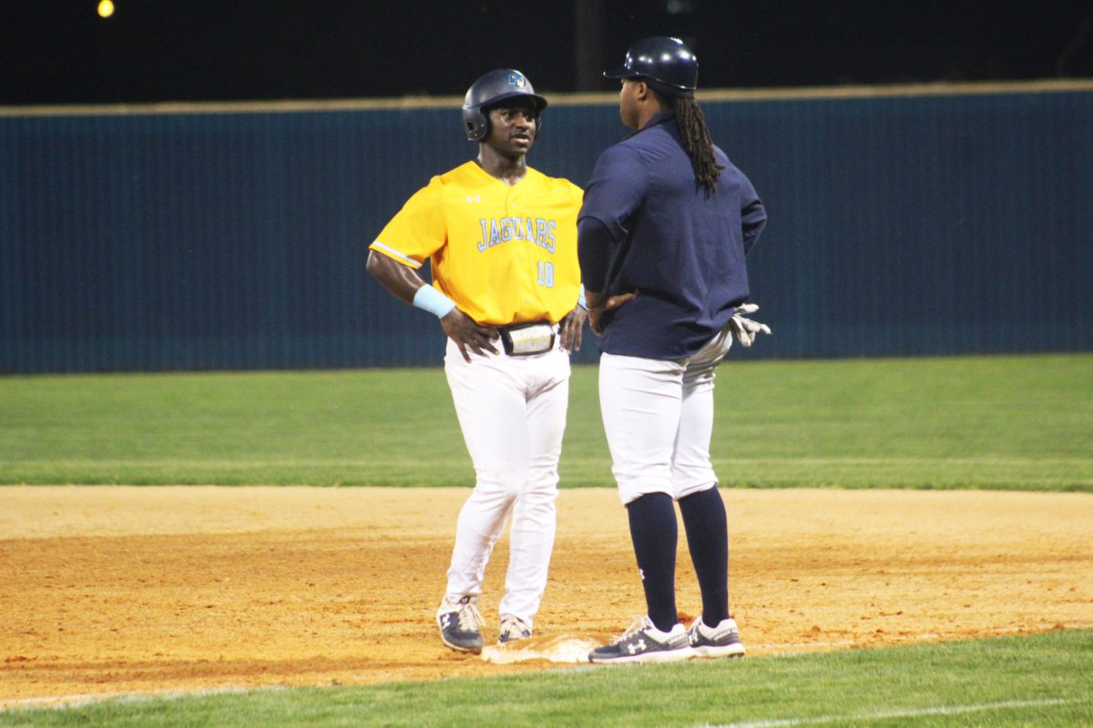 Assistant Coach T.J. Perkins talks with Zavier Moore while on 1st base on March 3, at Lee Hines Field. (Sean Musgrow/ DIGEST)