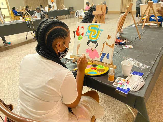 Annika Robinson. a freshman English major, painting her canvas colorfully at the Freshmore's Trap N Paint held inside the Student Union's Ballroom on February 1. (Te'yanah Owens/DIGEST)