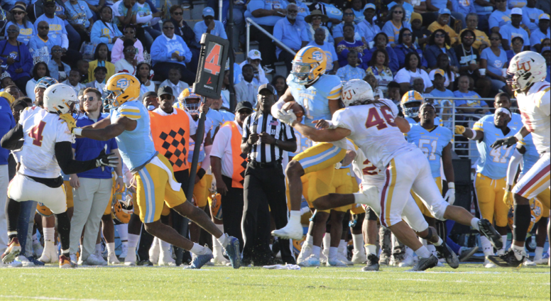 Graduate Student, quarterback Harold Blood muscles through an Oakland defender in hopes to reach the end zone.&#160;