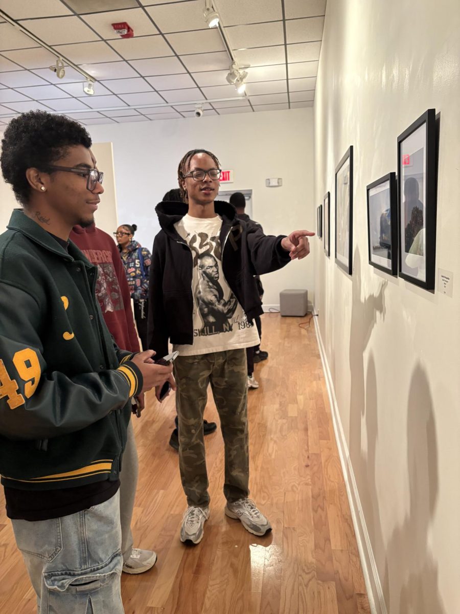 Students taking the time to observe and discuss the art on display during the 'Beauty on the Bluff' Opening reception on February 5, in the Hayden Hall Art Gallery.